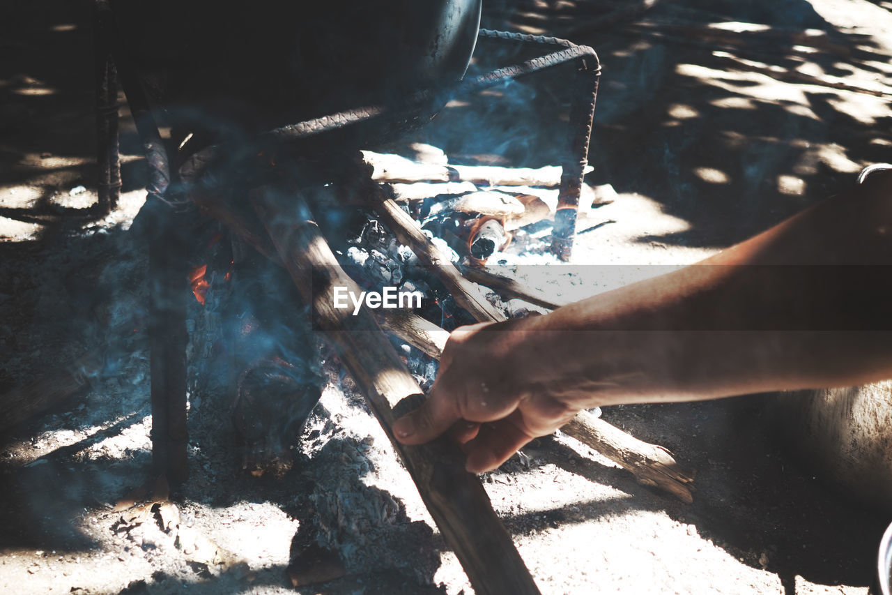 Cropped hand cooking food on field