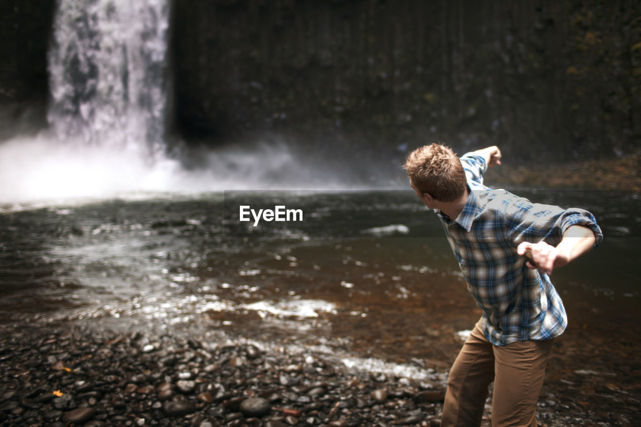 Man throwing stone at waterfall