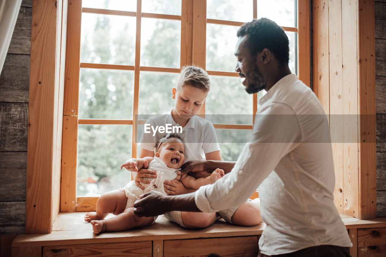 Father and son sitting on window