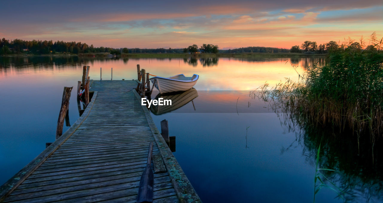 Pier on lake against sky during sunset