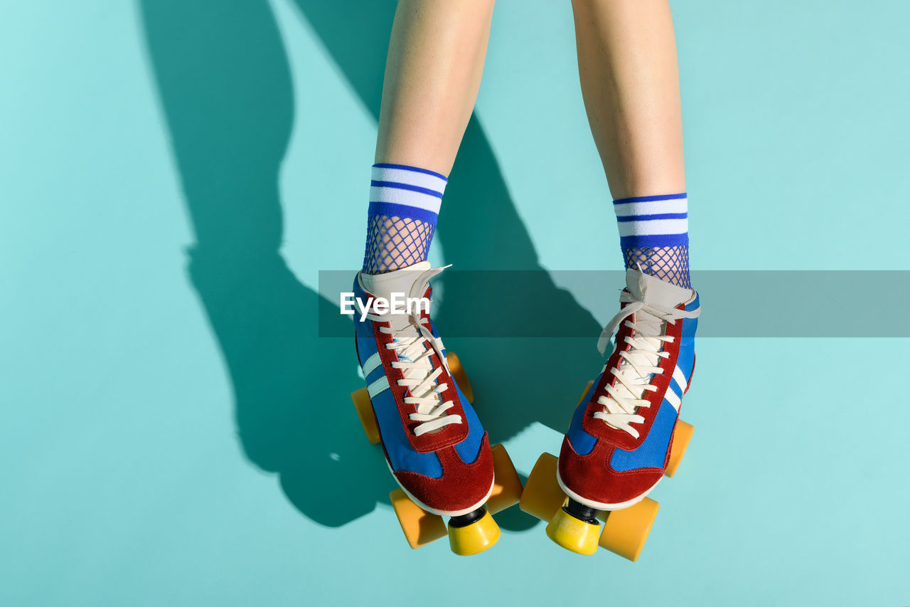 LOW SECTION OF WOMAN STANDING ON MULTI COLORED BLUE BACKGROUND