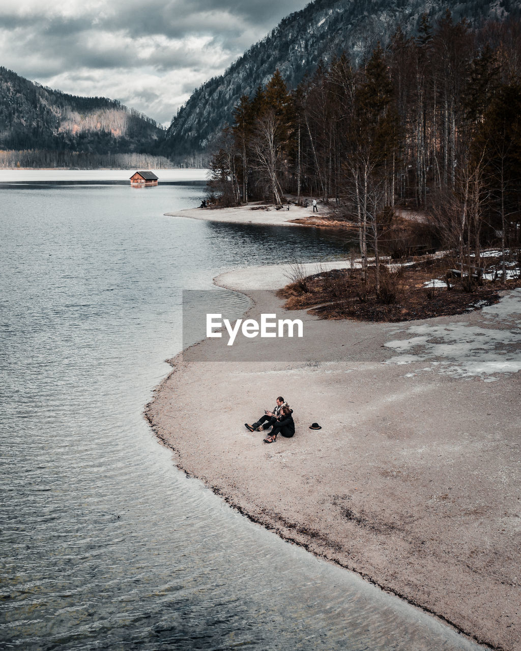 High angle view of couple sitting by lake against trees