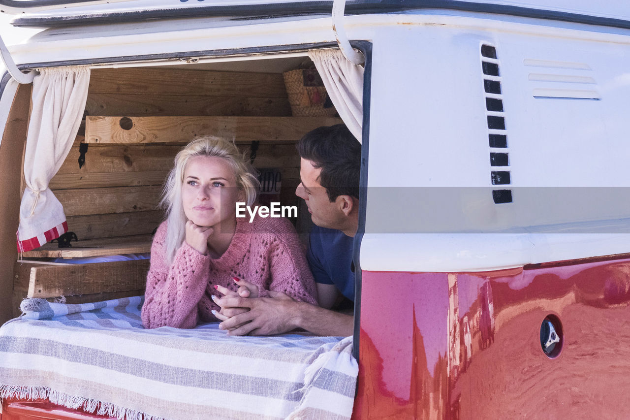 Smiling young couple relaxing in camper van