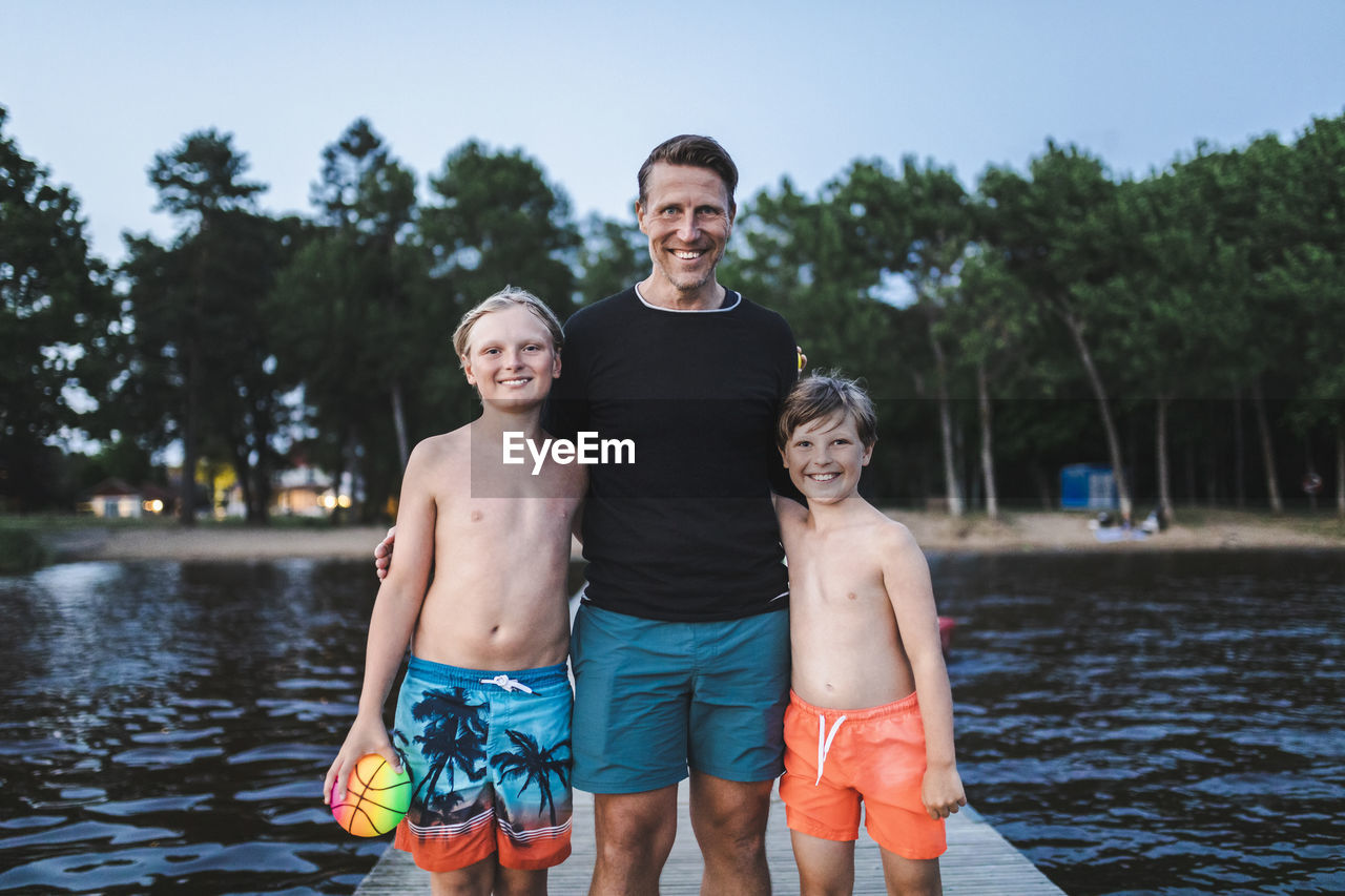 Portrait of smiling father with sons standing on jetty during weekend