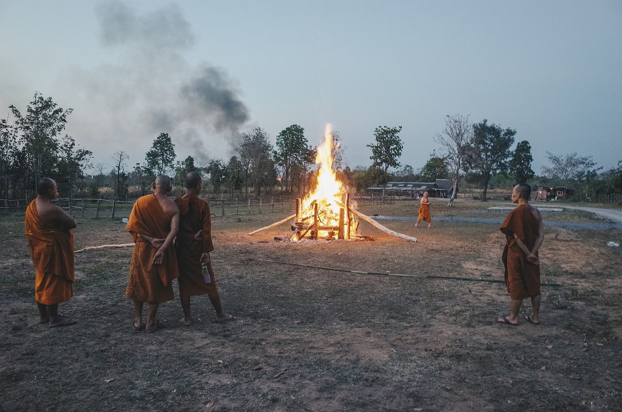 GROUP OF PEOPLE BY BONFIRE ON STREET