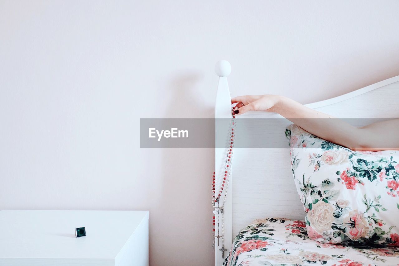 Cropped image of woman hand with bead necklace on headrest at home