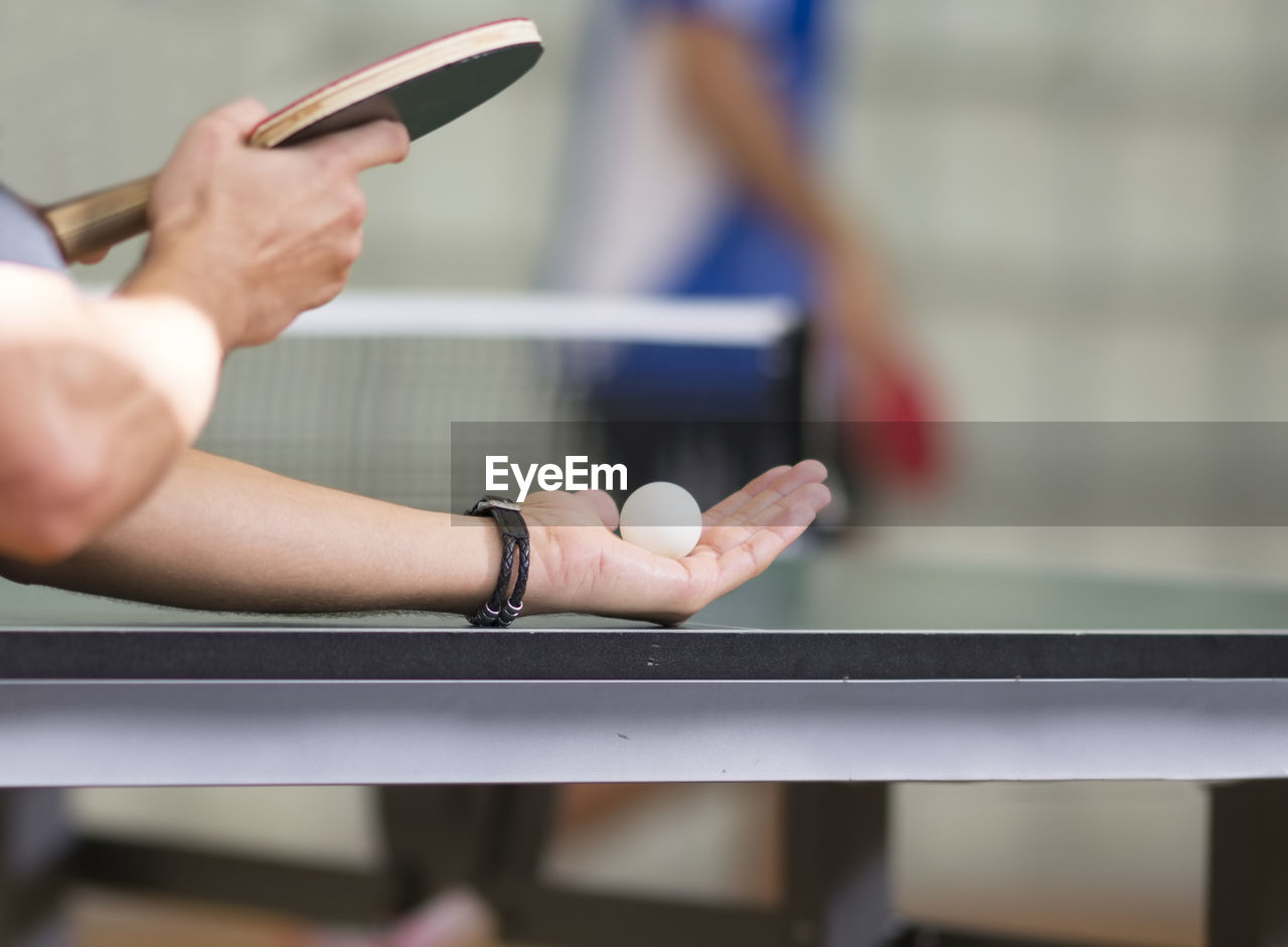 Cropped hands of man playing table tennis