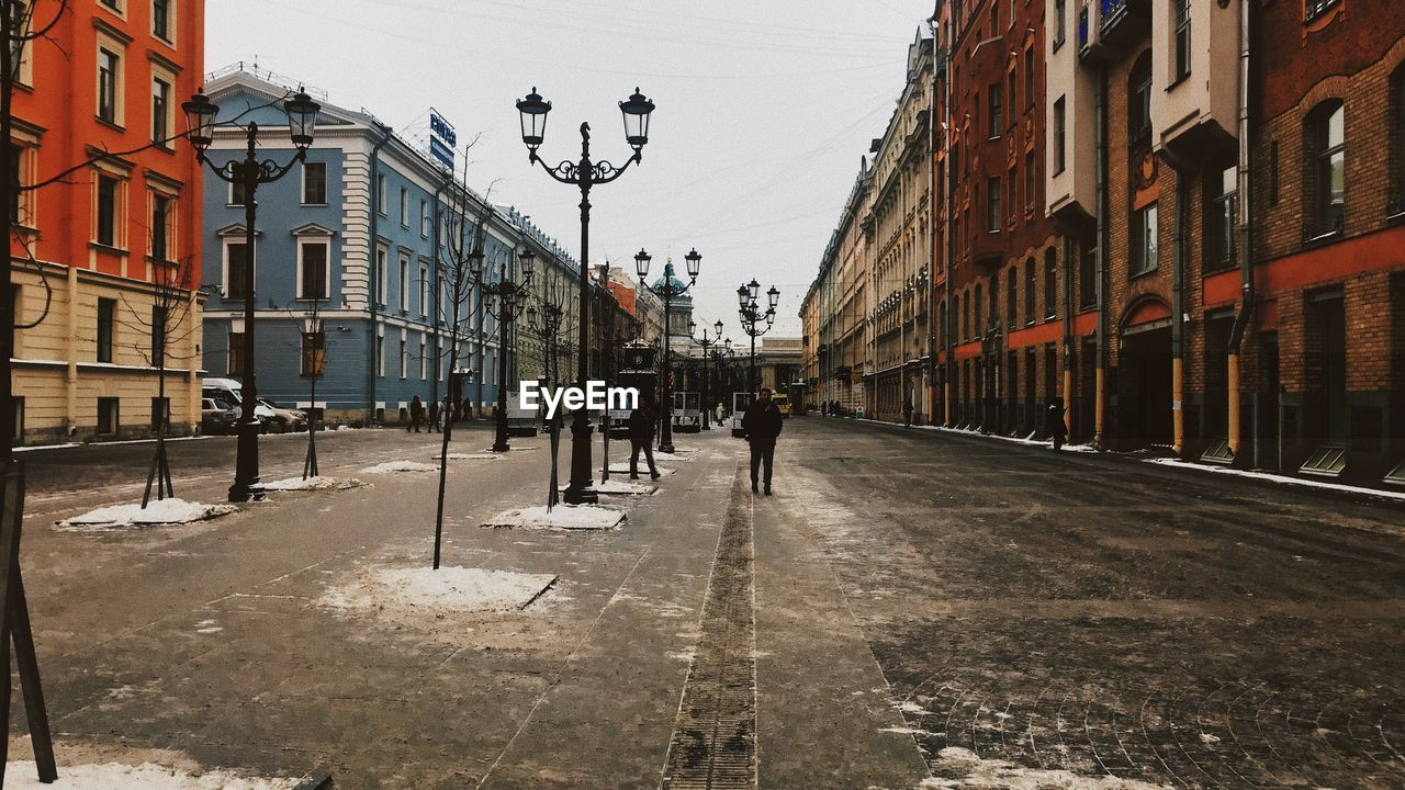 PEOPLE WALKING ON CITY STREET AMIDST BUILDINGS