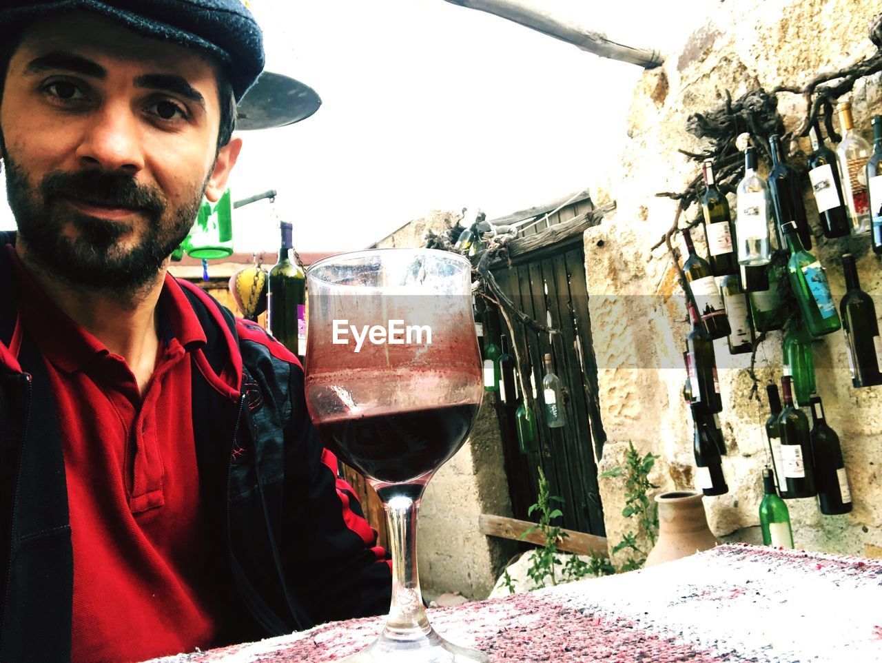 PORTRAIT OF YOUNG MAN DRINKING FROM GLASS OUTDOORS