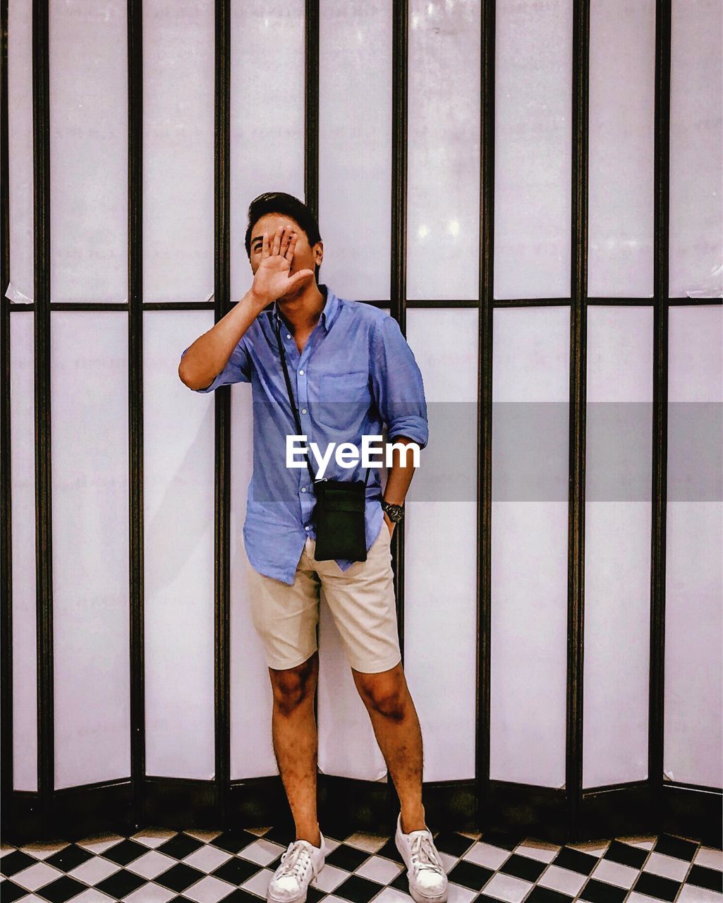 Full length of young man standing against striped wall