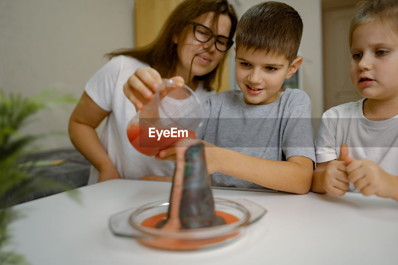 Mom and children at home are conducting an experiment with a volcanic eruption.