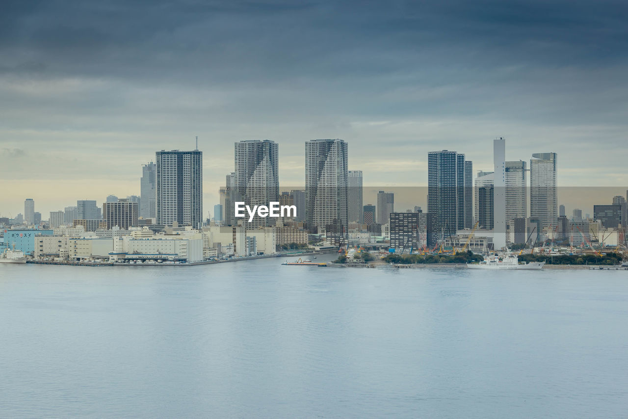 Sea and modern buildings in city against sky