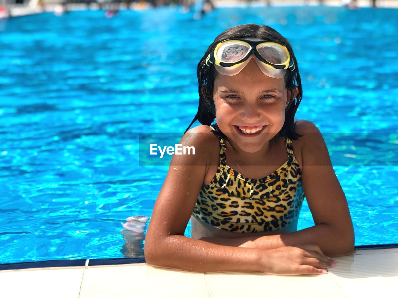 Portrait of smiling girl in swimming pool on sunny day