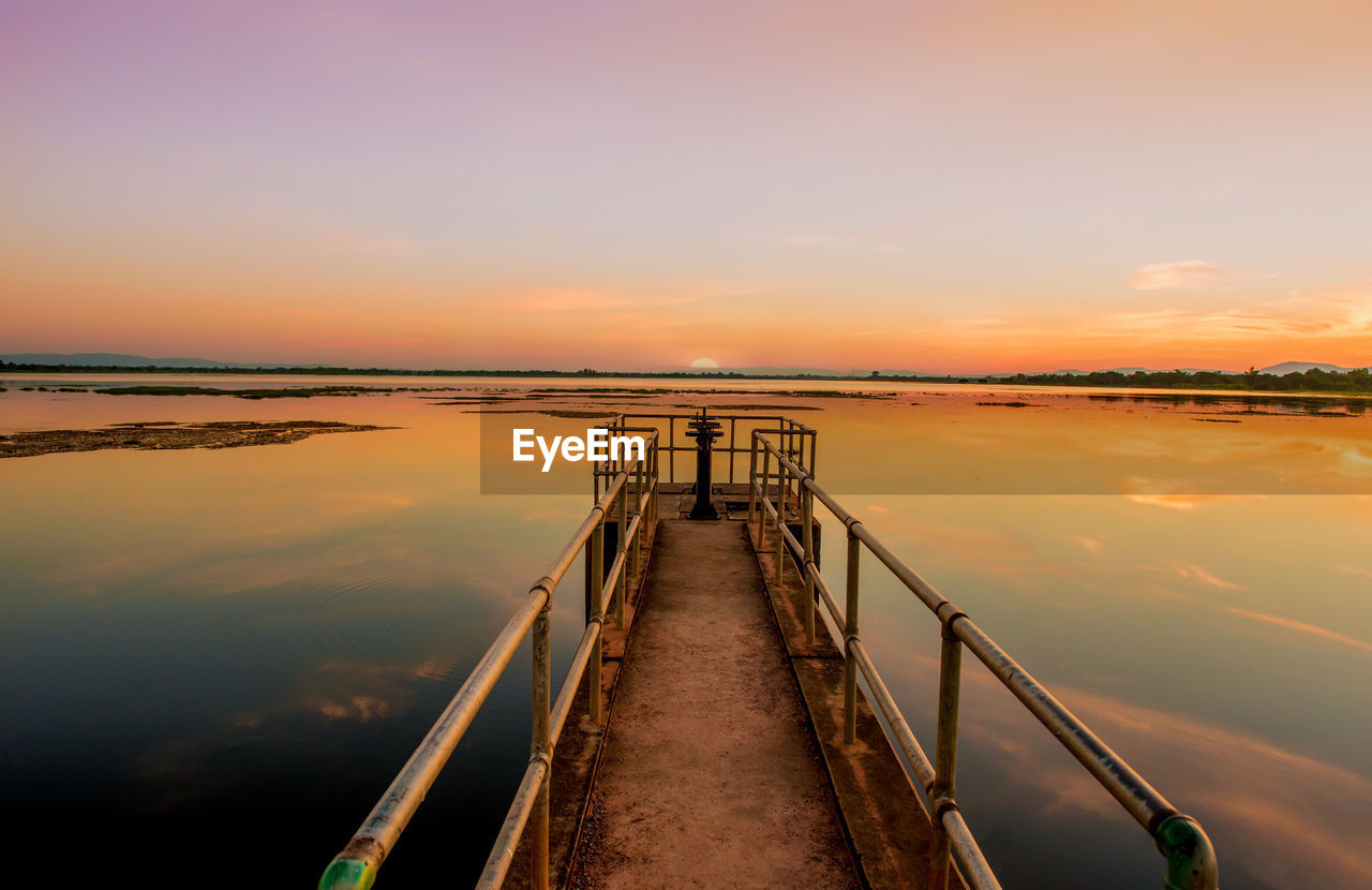 Pier over lake against sky during sunset