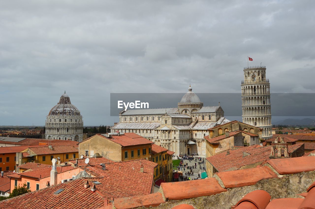 Historic leaning tower of pisa in city against cloudy sky
