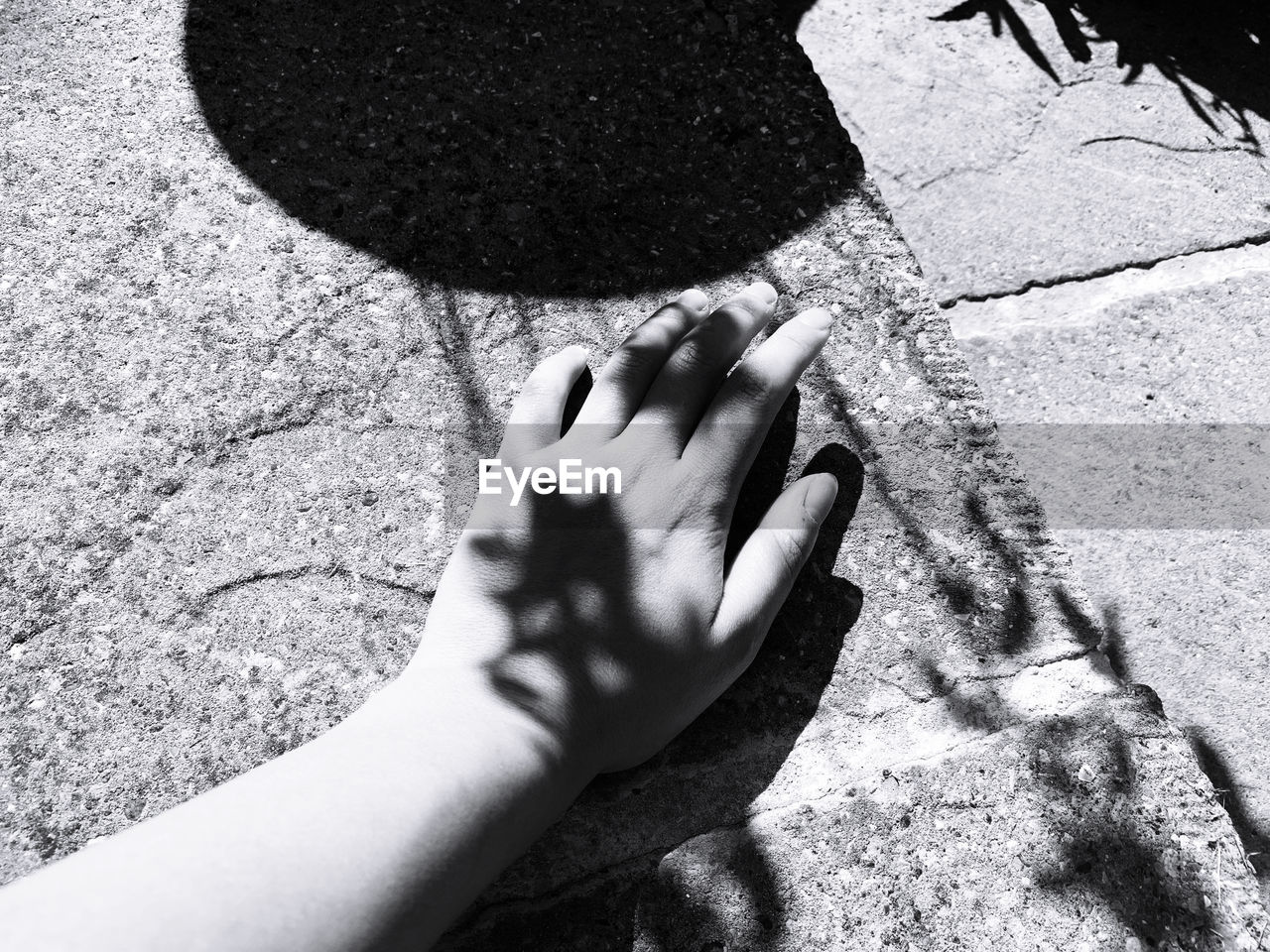 HIGH ANGLE VIEW OF HUMAN HAND TOUCHING SHADOW ON FLOOR