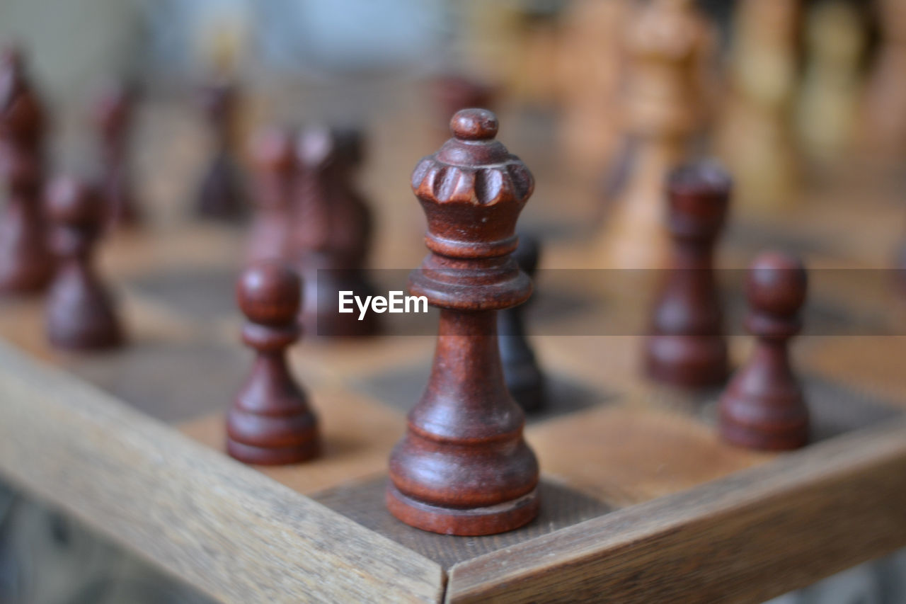 CLOSE-UP OF CHESS PIECES ON WOODEN BOARD