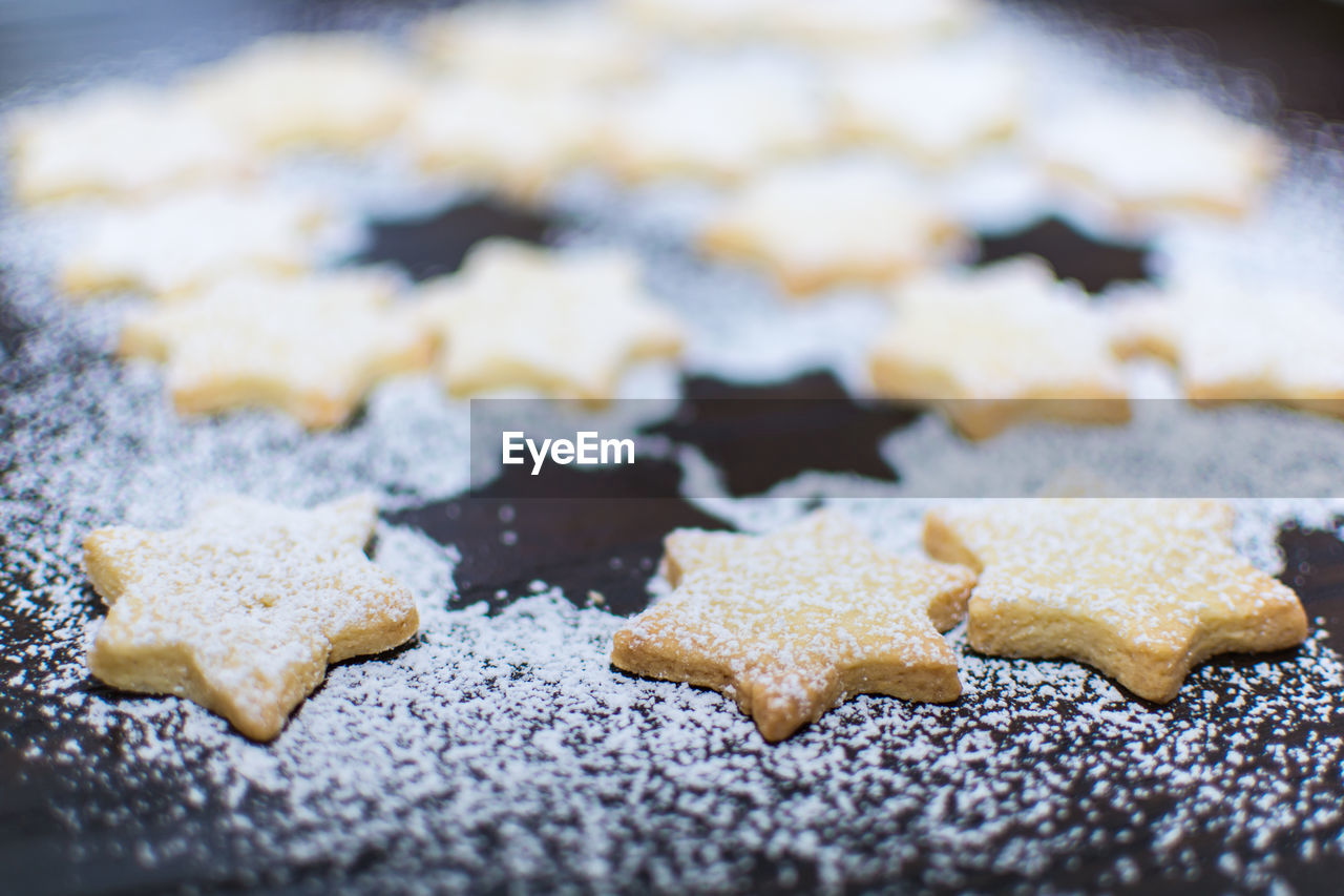 Powdered sugar above star shaped christmas cookies