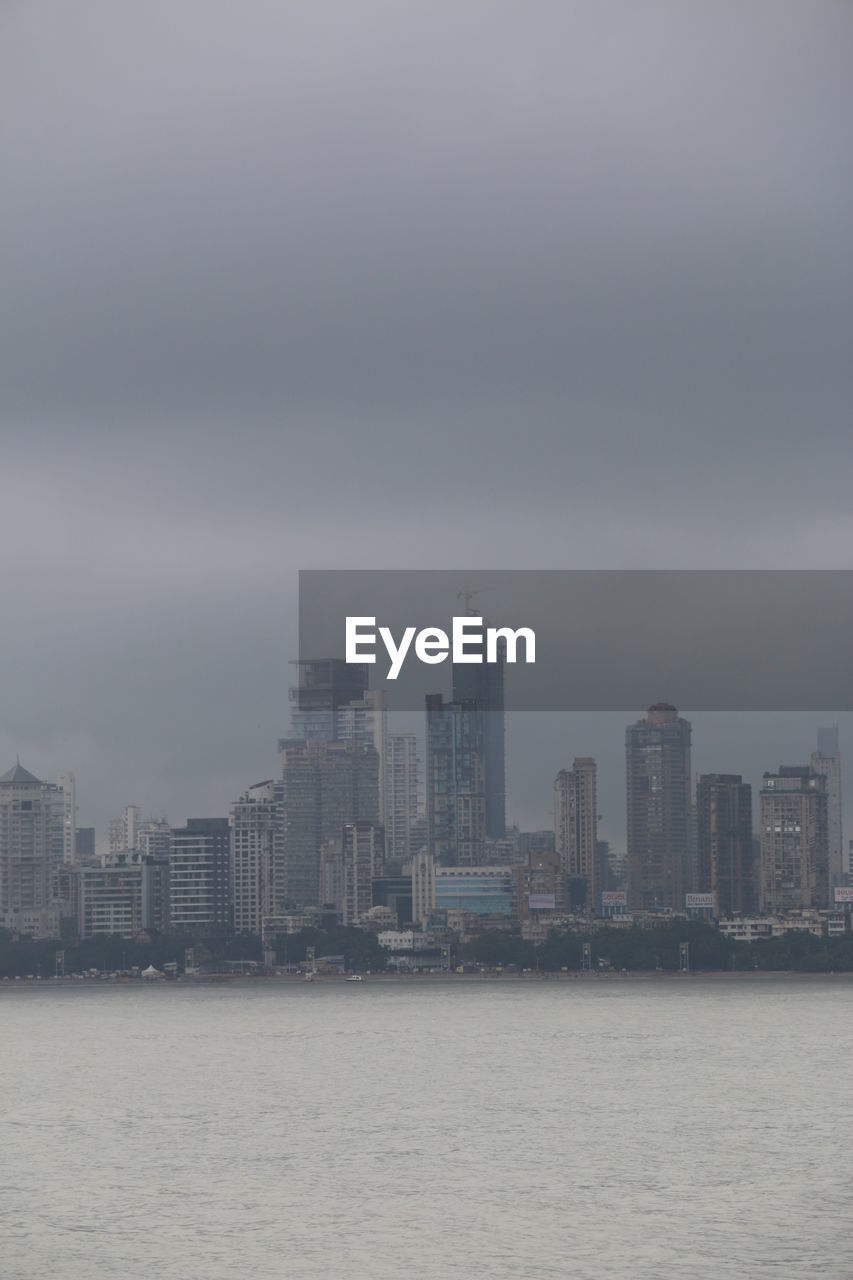 Sea by cityscape against sky