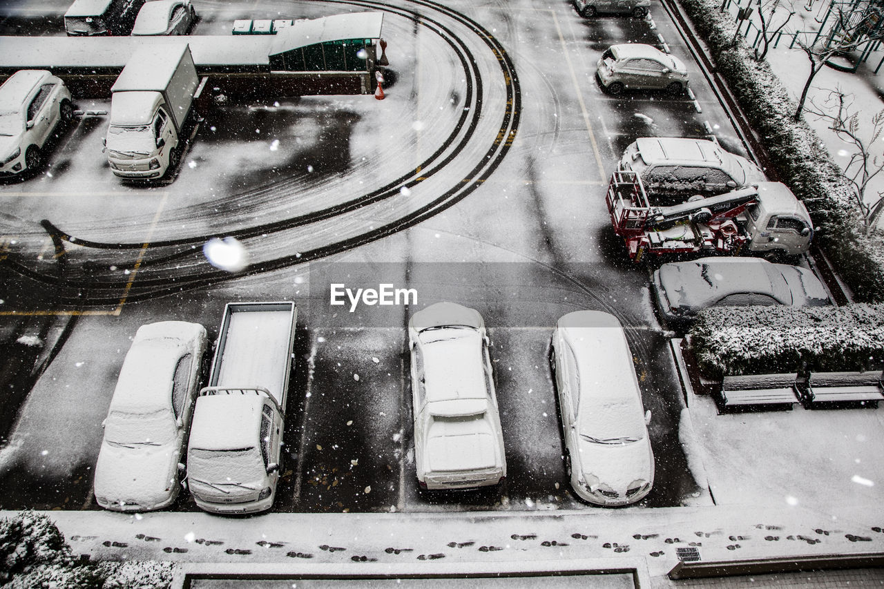 High angle view of snow covered vehicles parked at parking lot