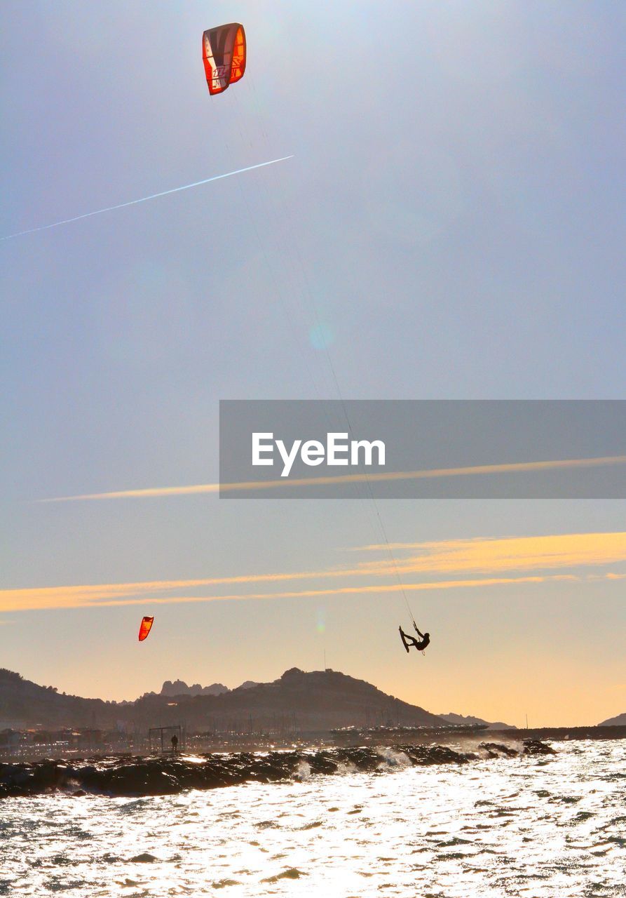 Person kiteboarding over sea against sky during sunset