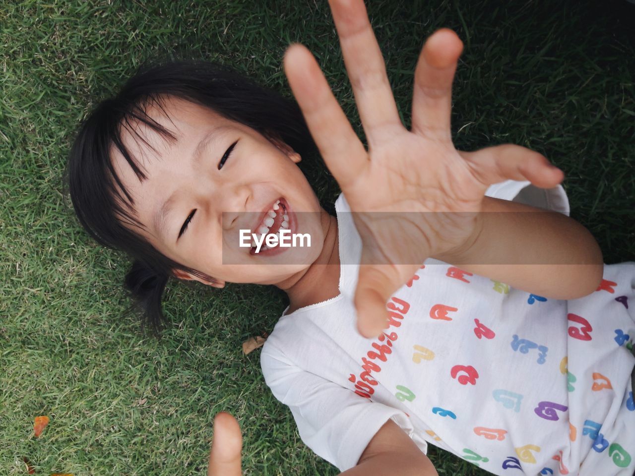 Directly above portrait of happy girl lying on grassy field