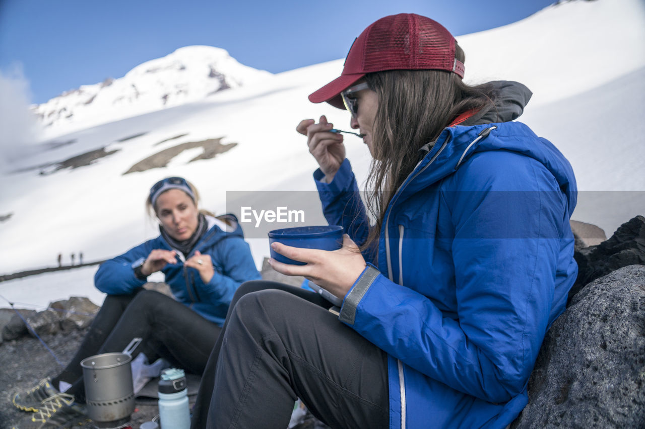 Two women eating breakfast and talking at base camp, mt. baker