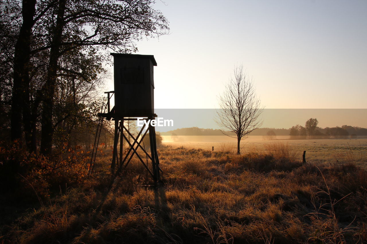 Silhouette hut on field against sky during sunset