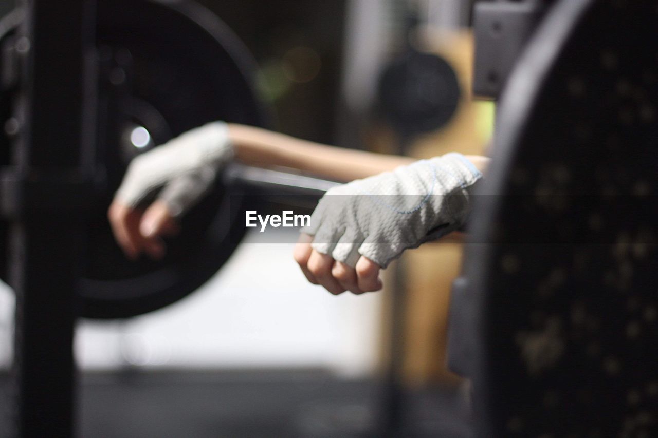 Cropped hands of person on barbell in gym