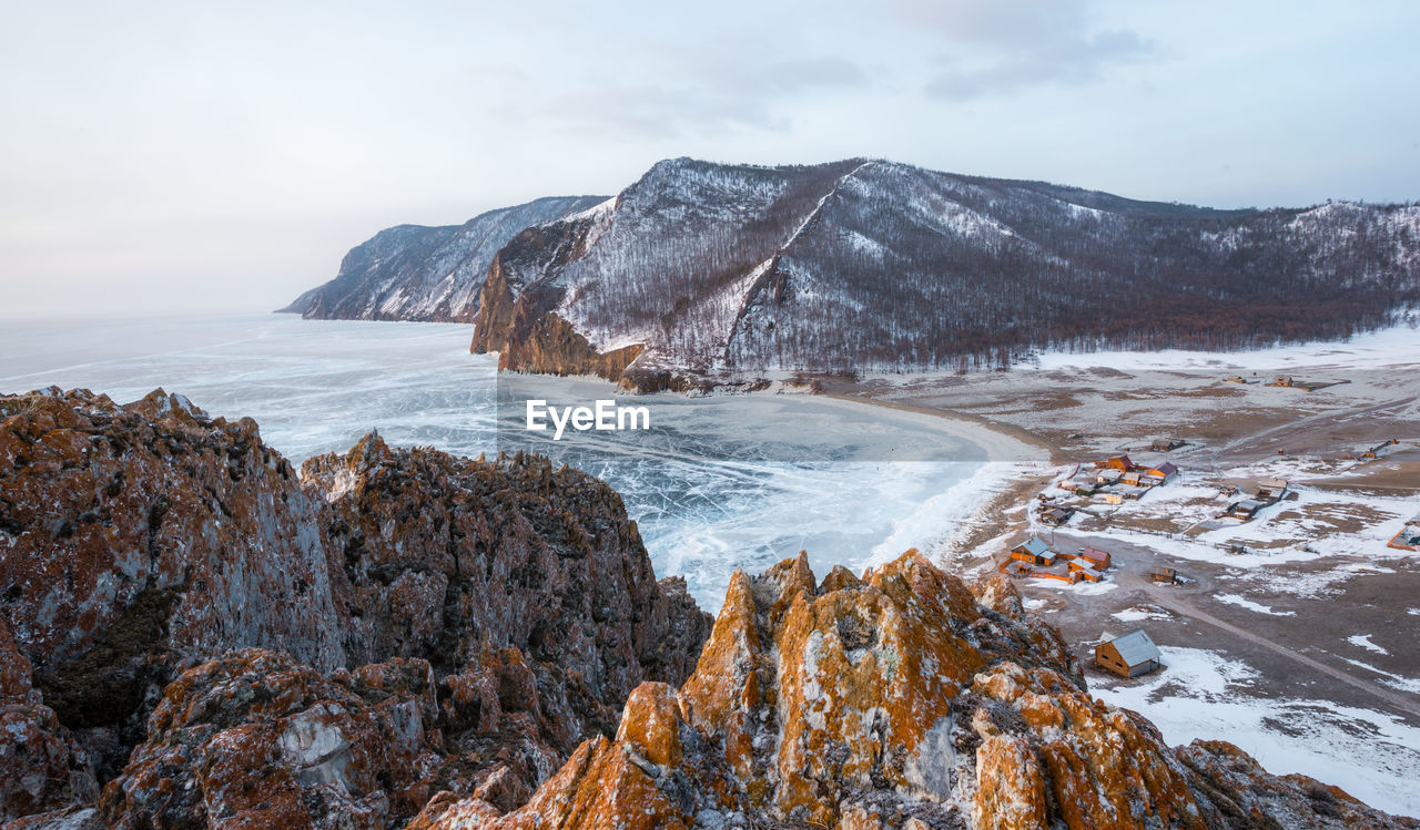 Scenic view of frozen sea by mountain against sky