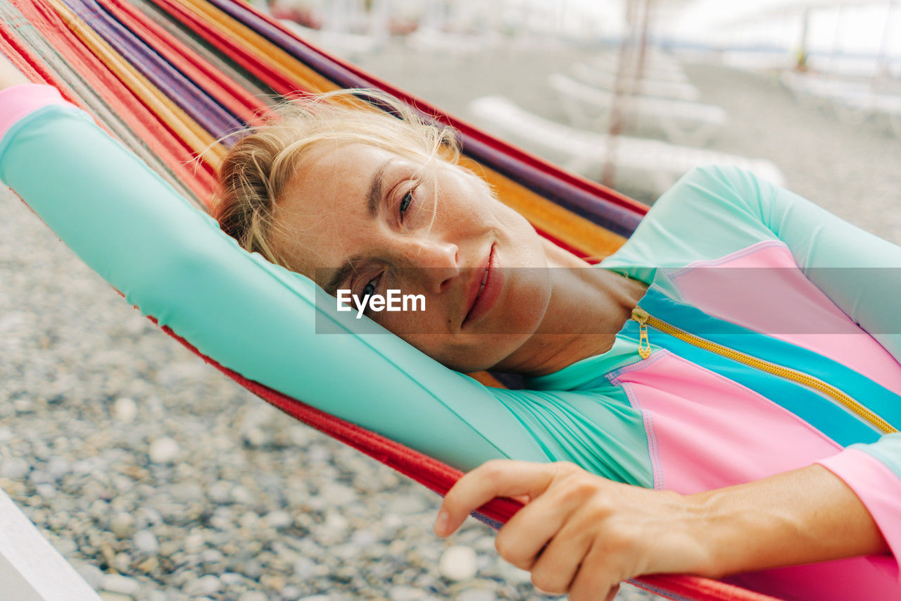 Happy smiling carefree young woman relaxing in a hammock on the beach.