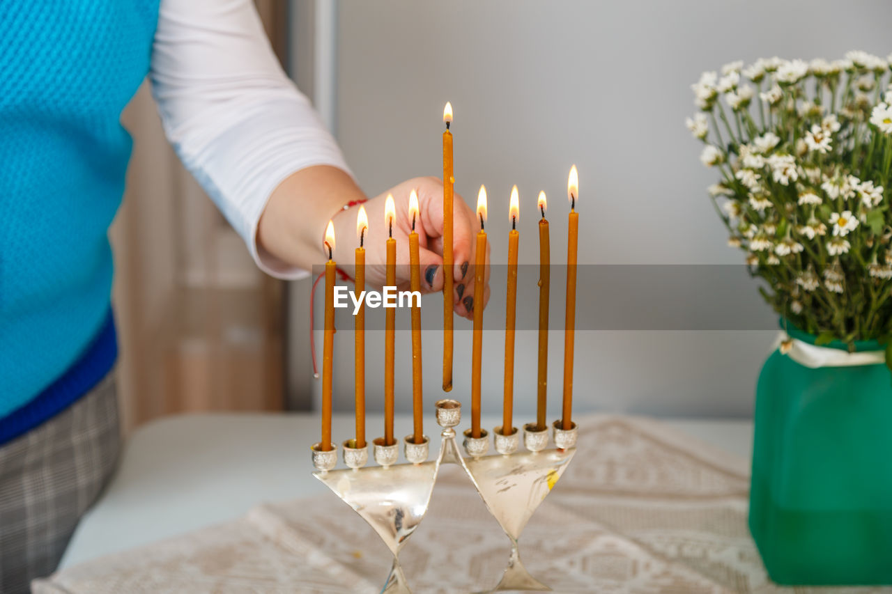 Midsection of woman holding candle on table