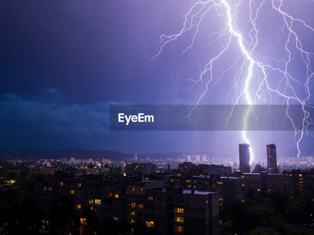 Lightning over illuminated buildings in city at night