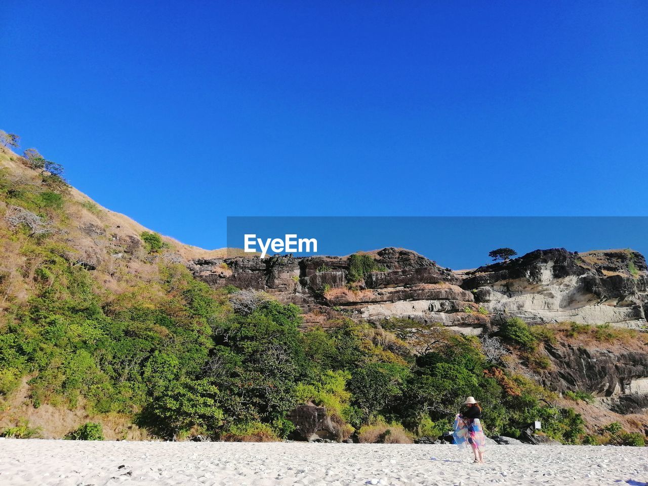 Woman standing on mountain against clear blue sky