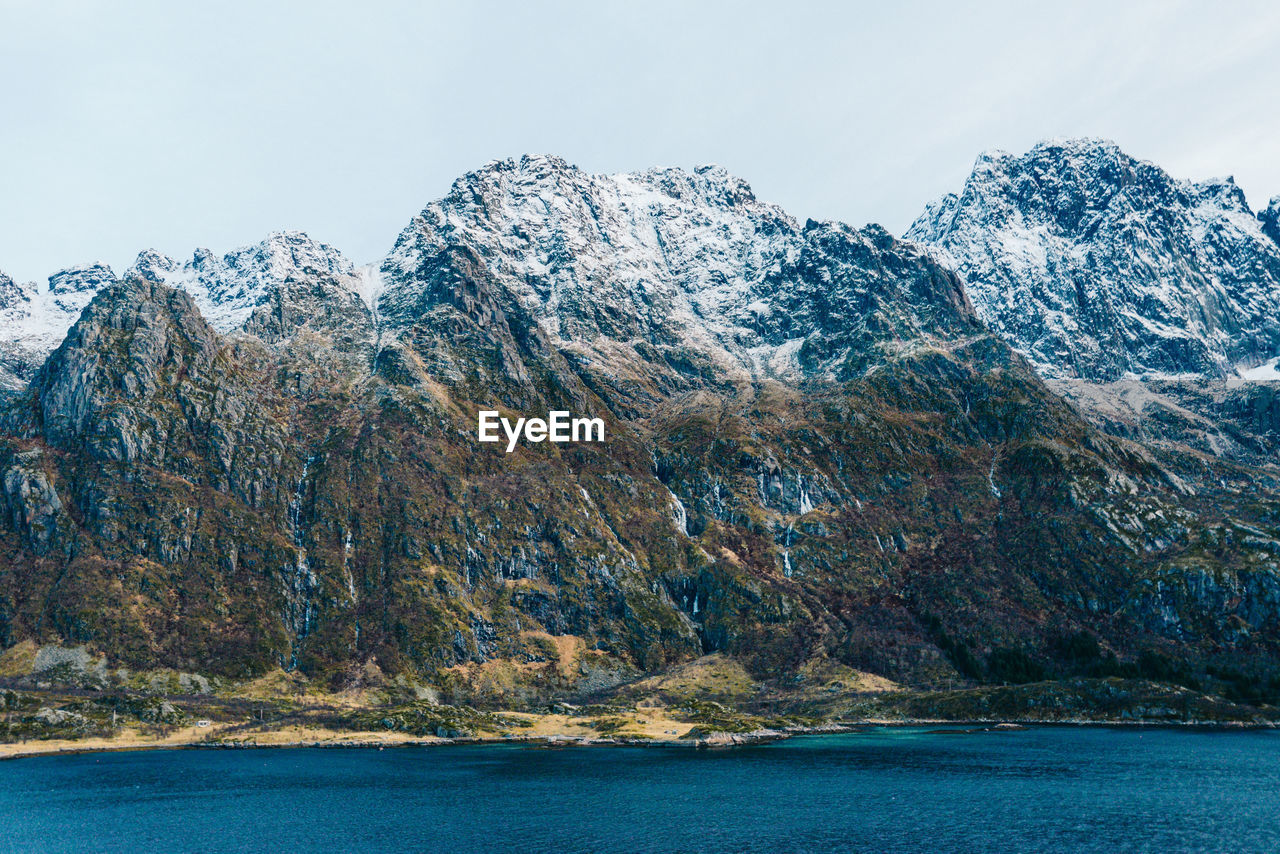 Scenic view of lake by snowcapped mountains against sky