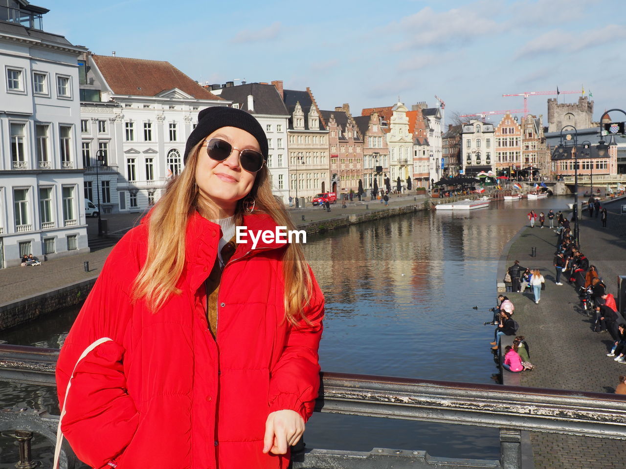 Portrait of beautiful woman standing by canal in city