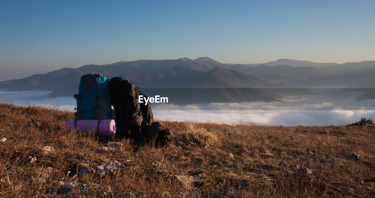 Backpacks on mountain against cloudscape