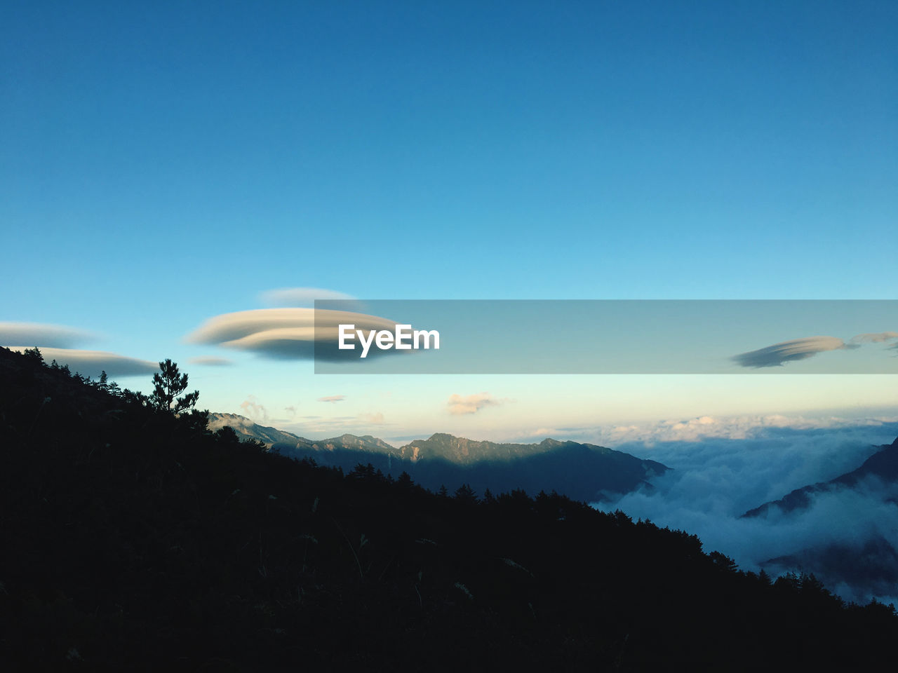 Scenic view of silhouette mountains against blue sky