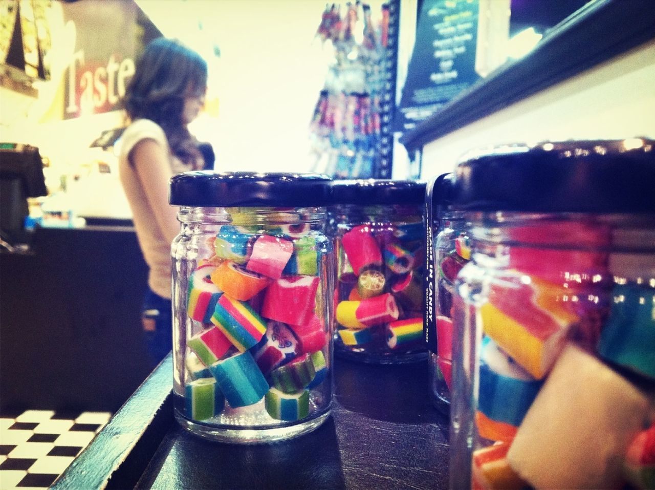 Close-up of candy jars with woman in background at store