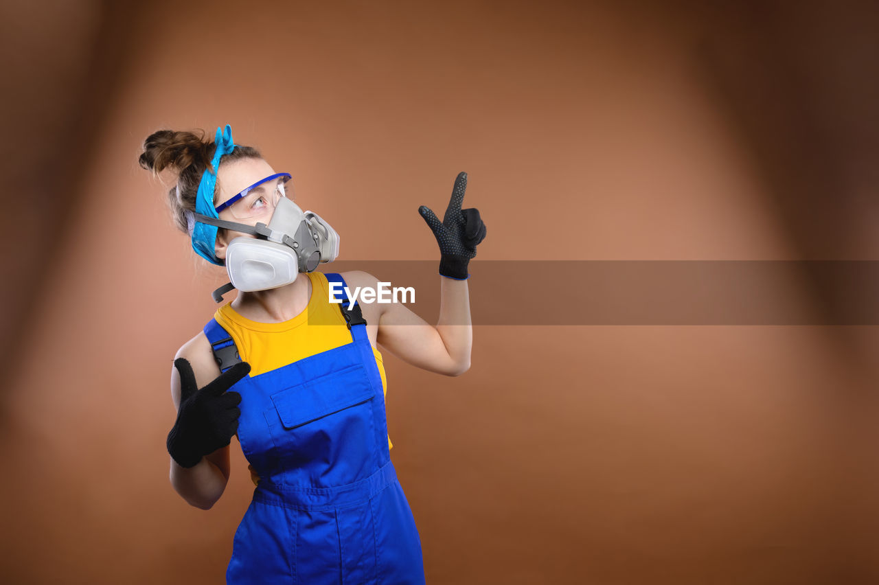 Young caucasian woman in construction uniform stands on a colored background