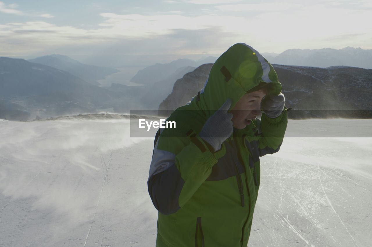 MAN WITH UMBRELLA ON SNOW COVERED MOUNTAINS