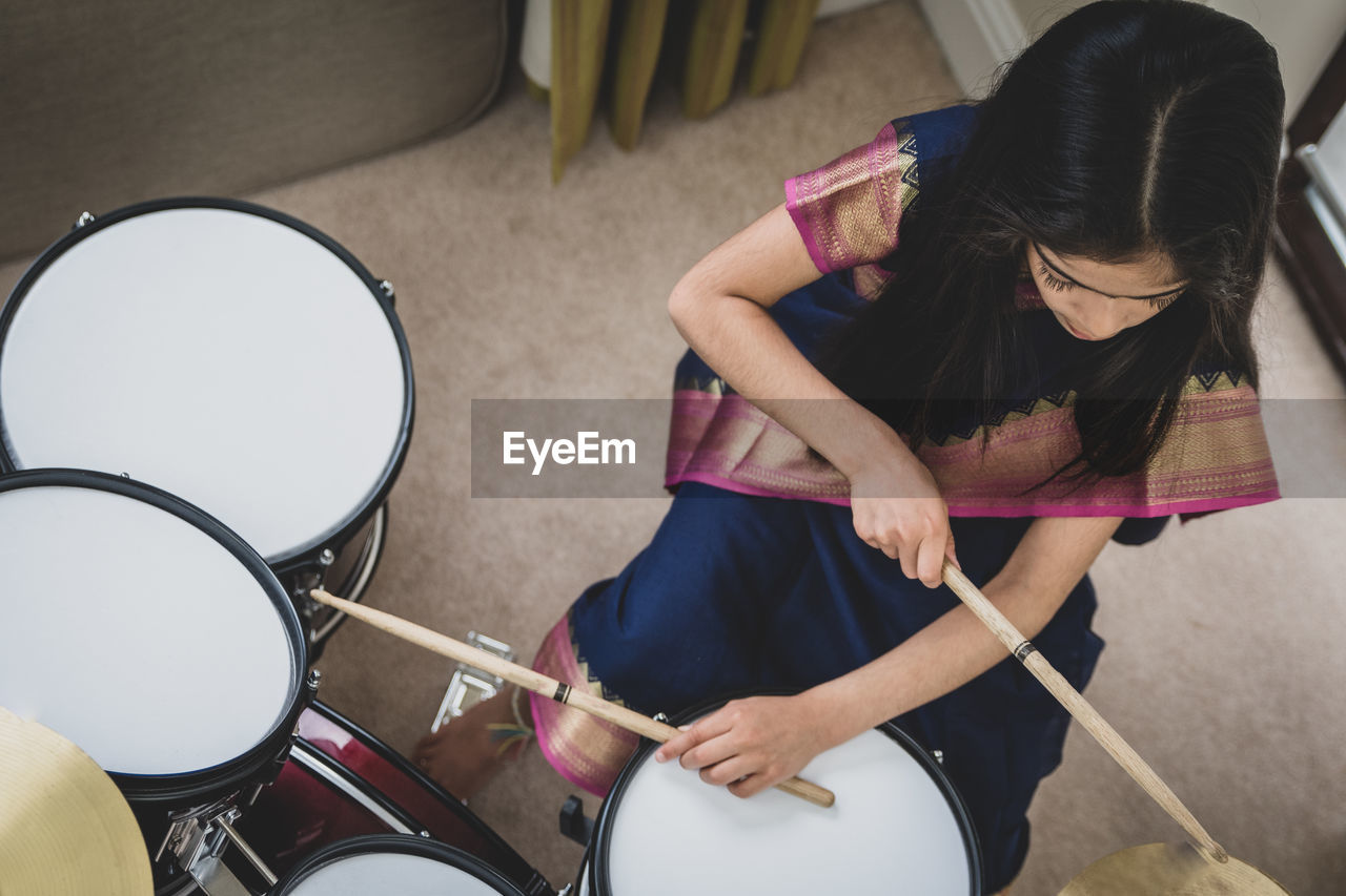 High angle view of school age girl playing drums.