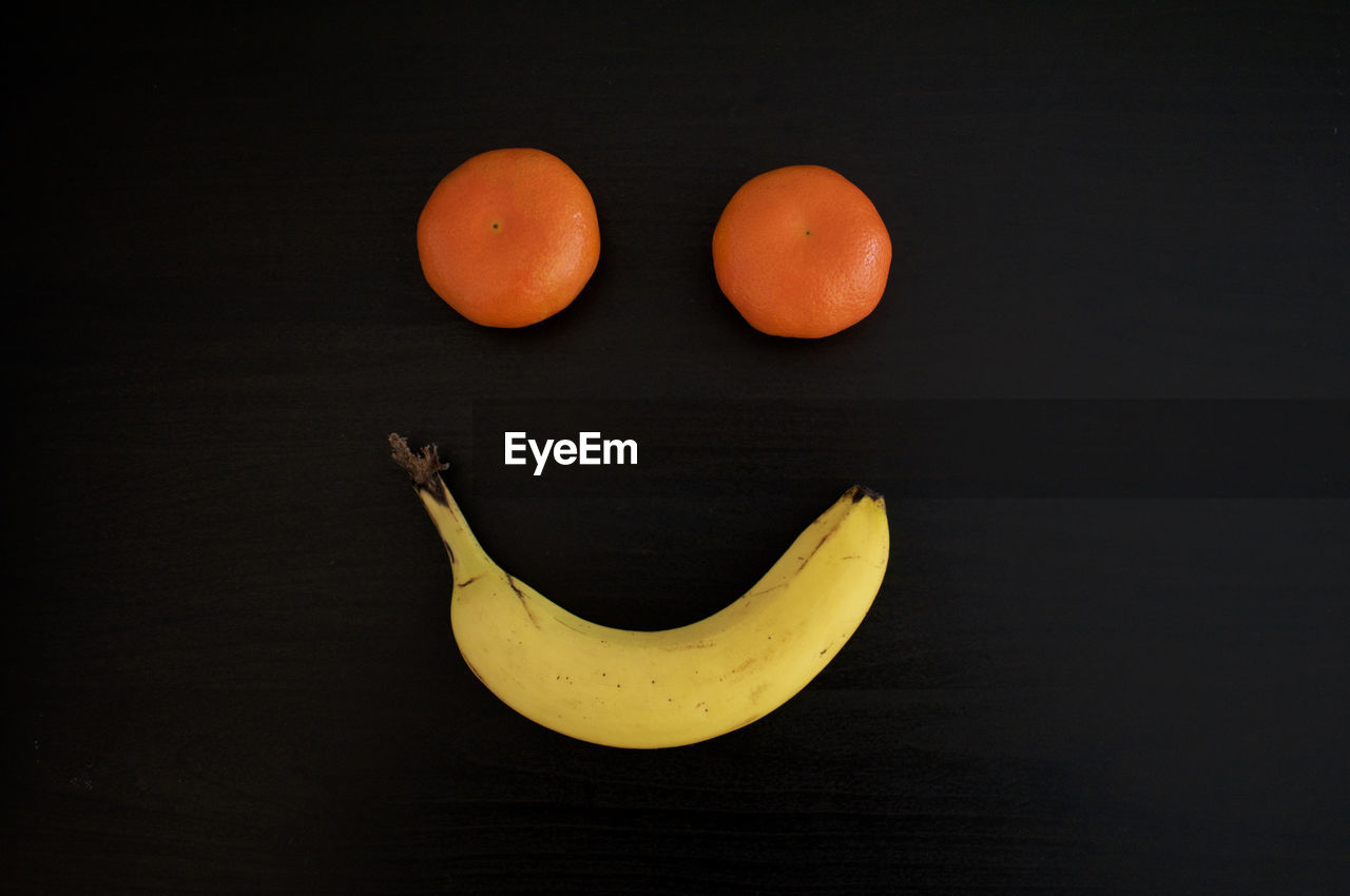 Smiling grimace made out with tangerines and a banana on a black background