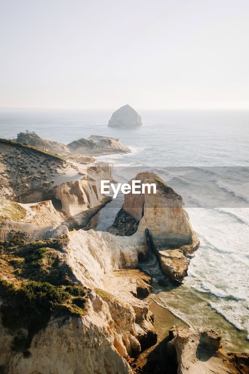 Rock formations by sea against clear sky