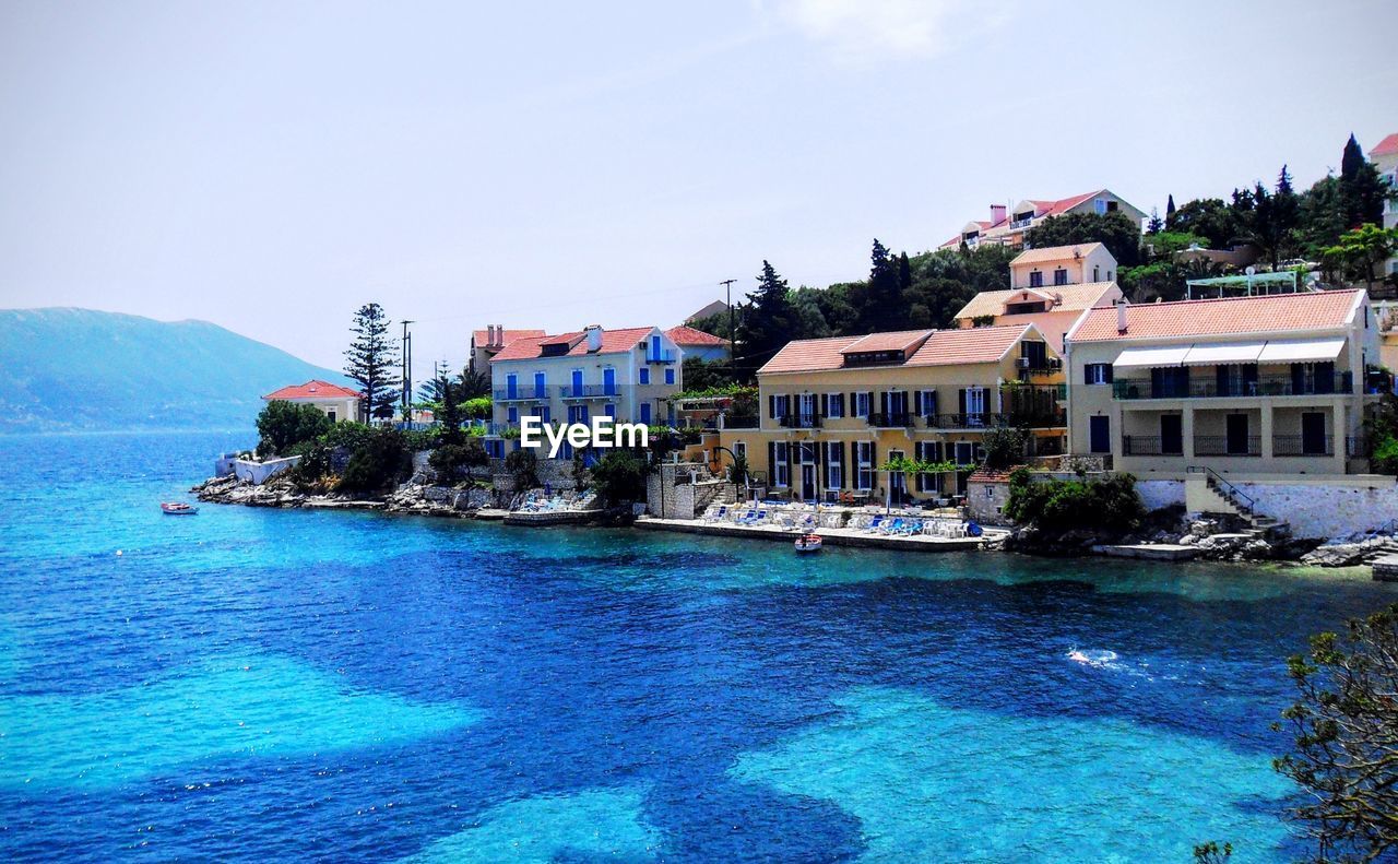 HOUSES IN FRONT OF SEA AGAINST SKY IN TOWN