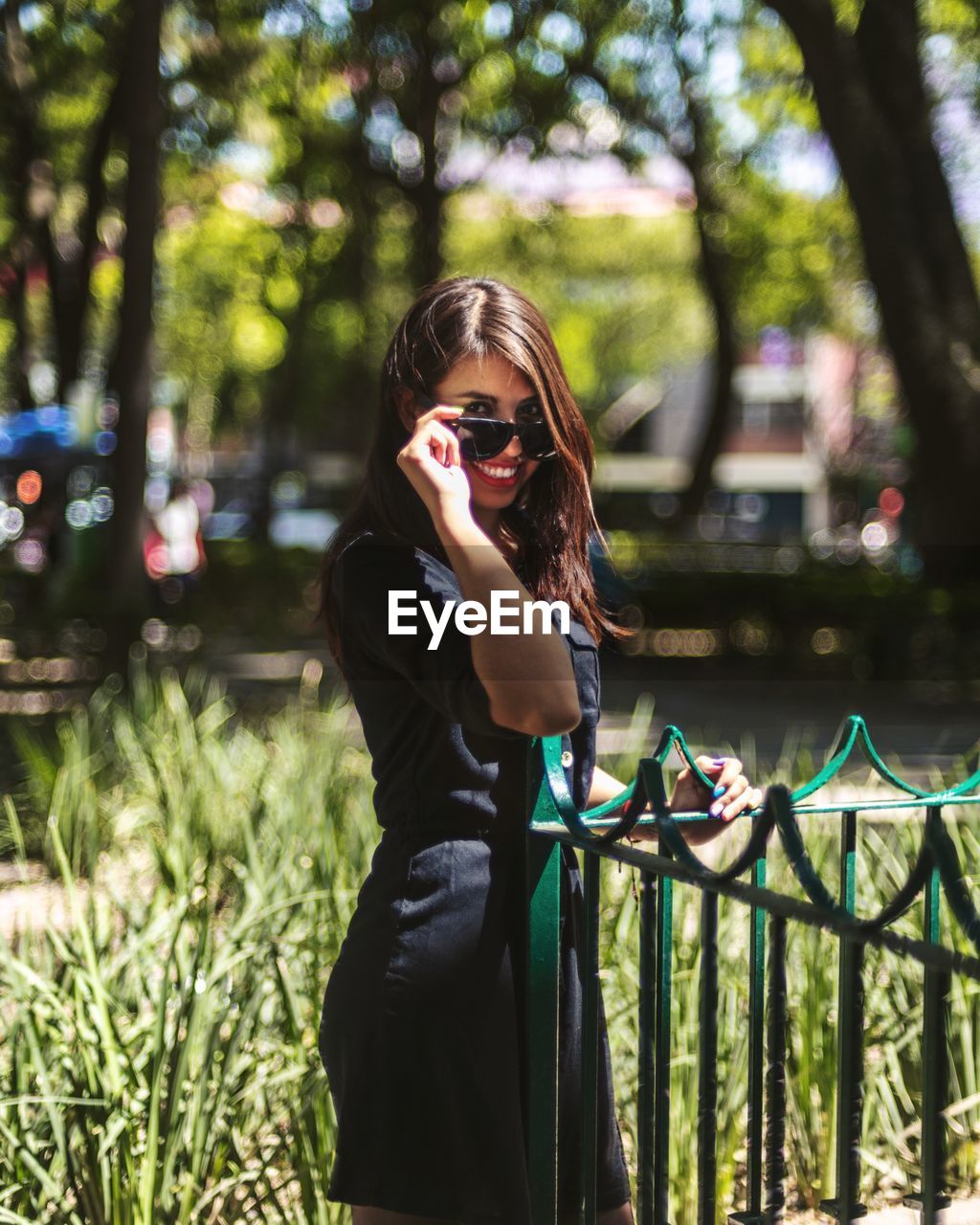 Portrait of woman wearing sunglasses standing by railing