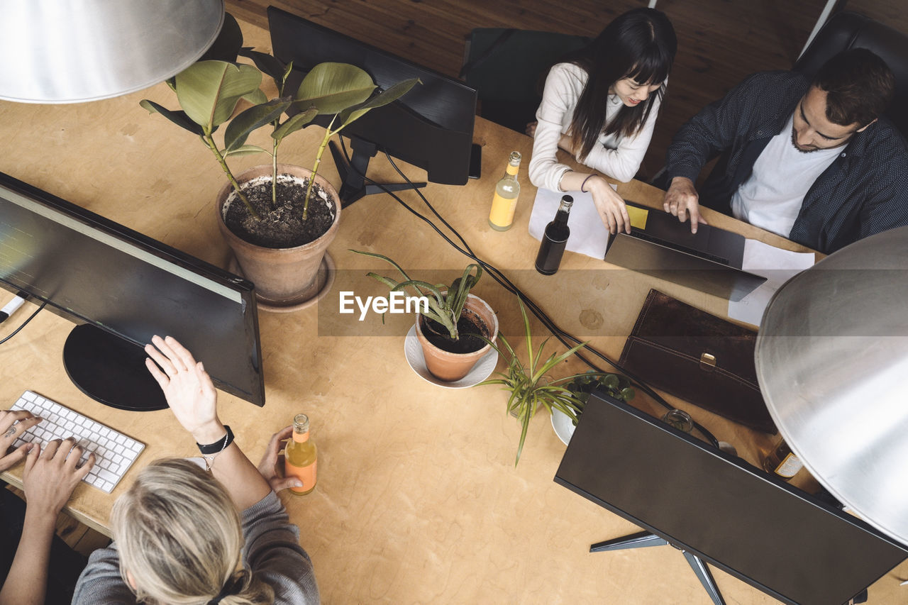 High angle view of coworkers discussing at workplace