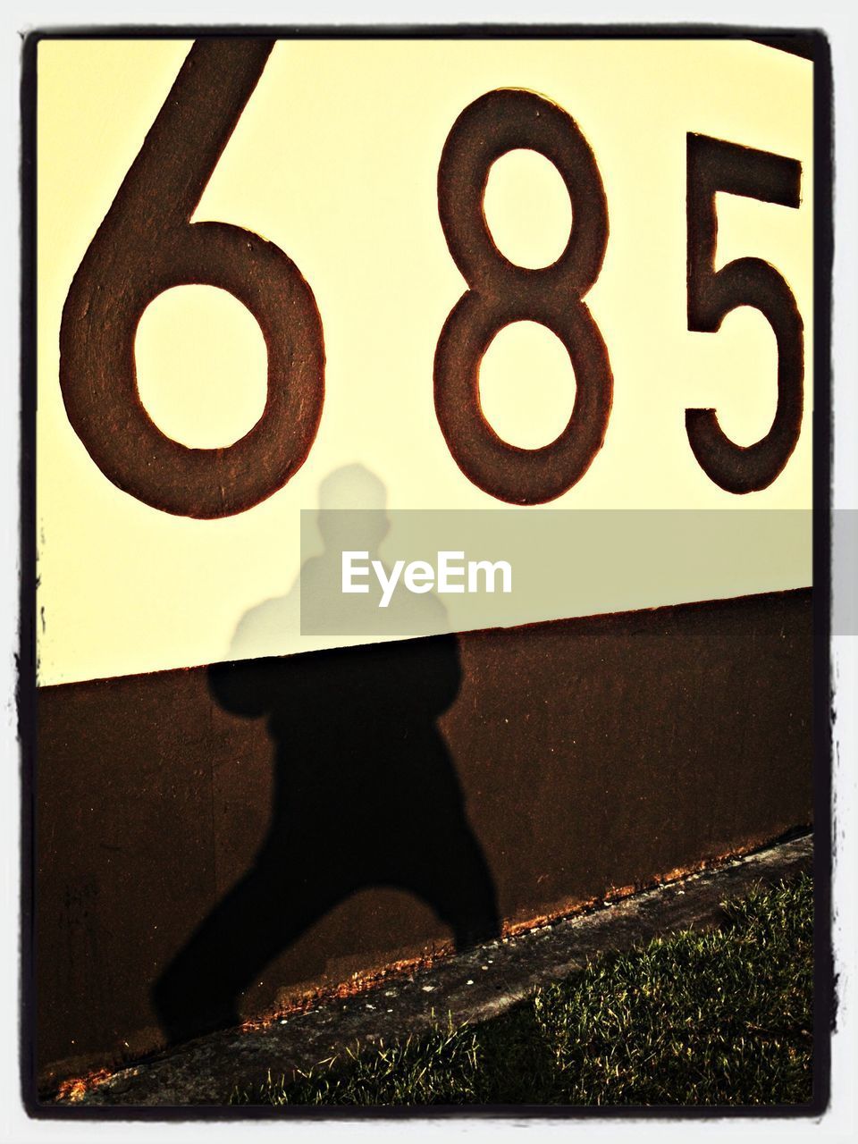 Silhouette of person against wall with number 685