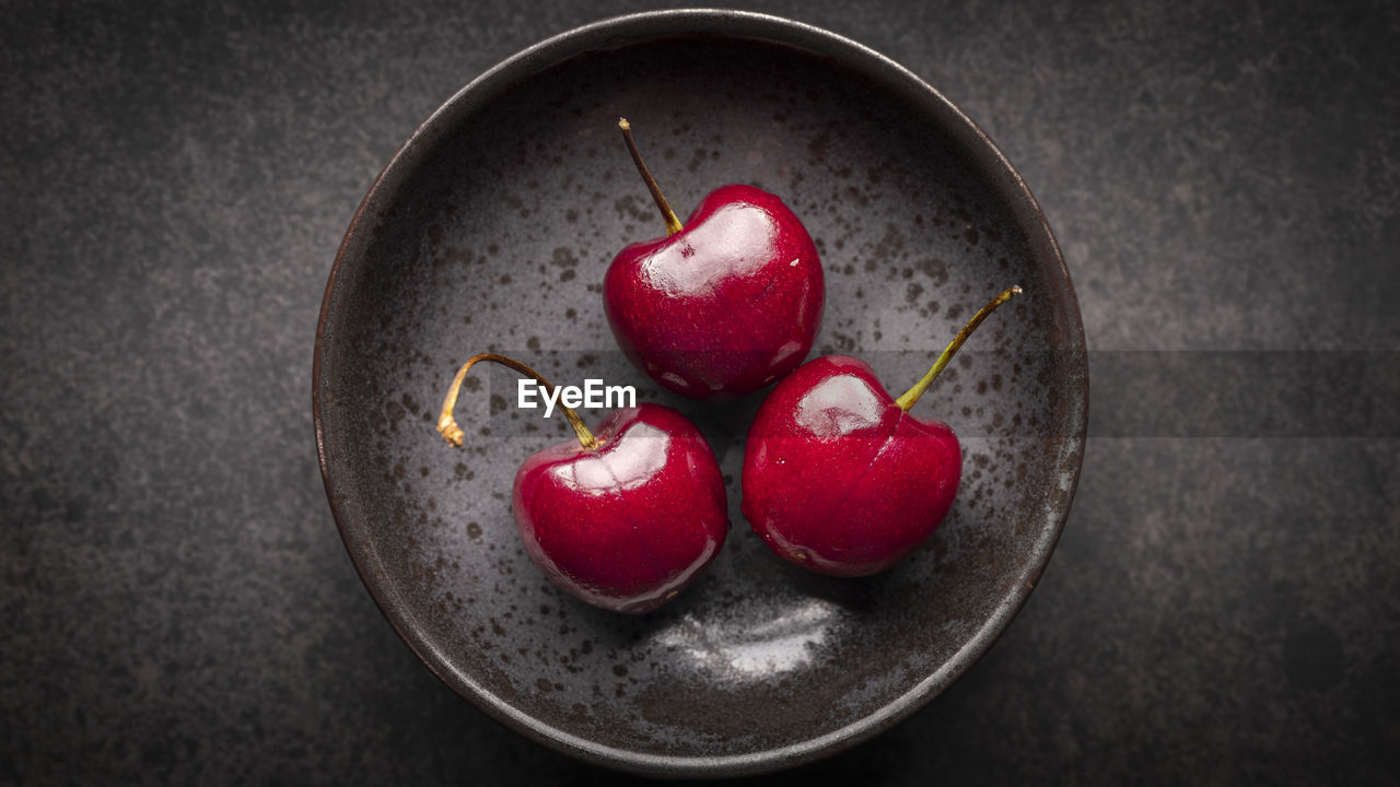 Top view, ripe red sweet cherries in rusty ceramic plate on dark tone texture background, cherry