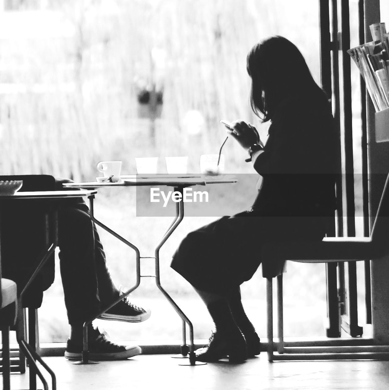 Woman sitting in restaurant chair while using smart phone